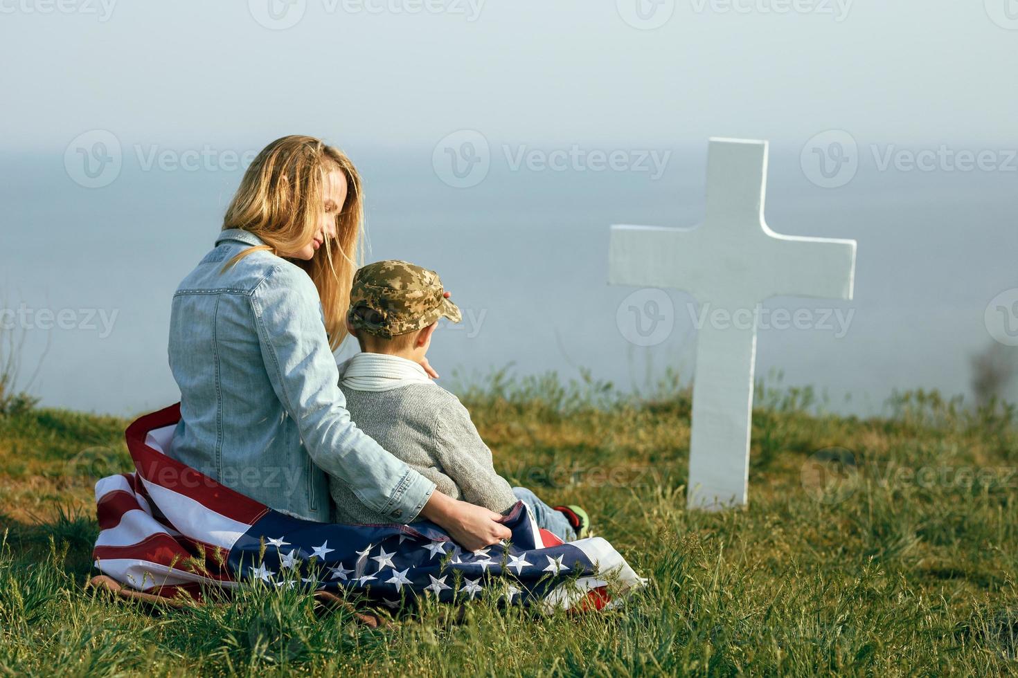 Mama und Sohn sitzen auf dem Grab eines Soldaten foto