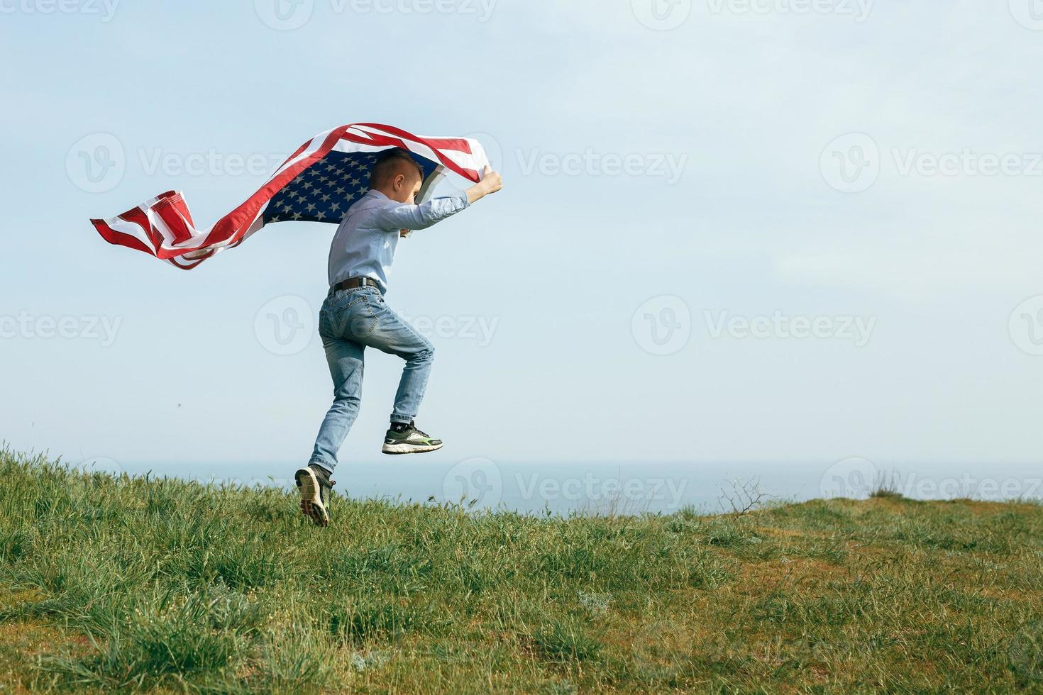 ein kleiner Junge läuft mit der Flagge der Vereinigten Staaten foto