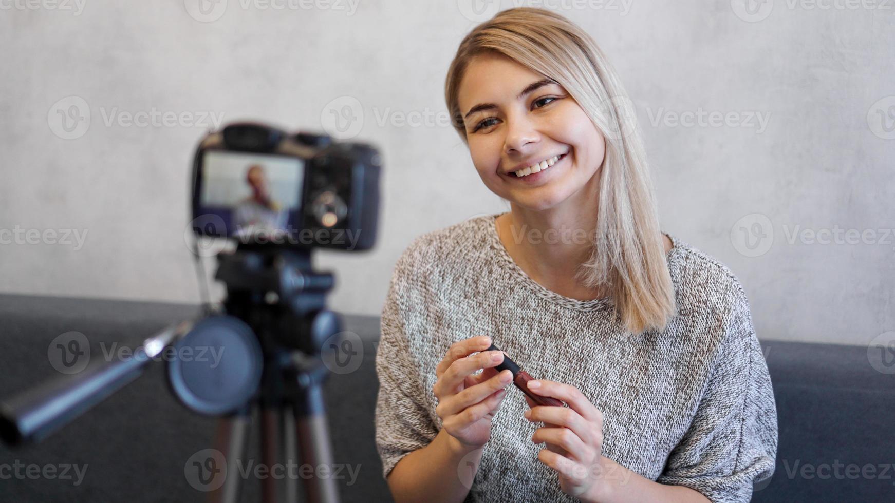 Vloggerin, die Lippenstift zeigt. Beauty-Bloggerin im Homestudio foto