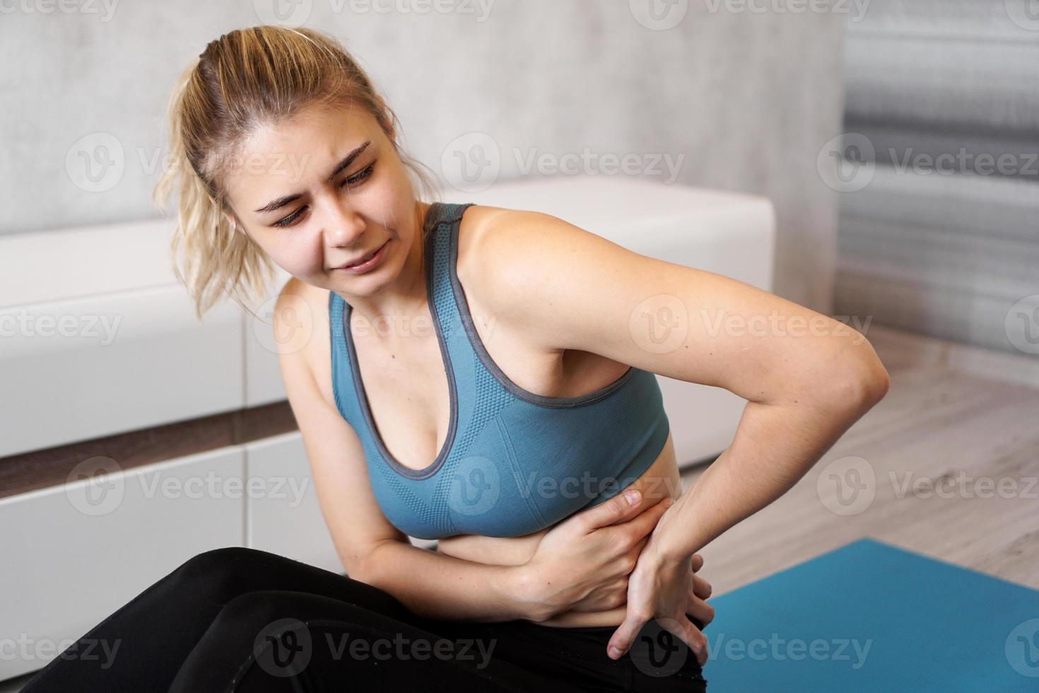 Porträt einer jungen Frau, die auf einer Yogamatte sitzt foto