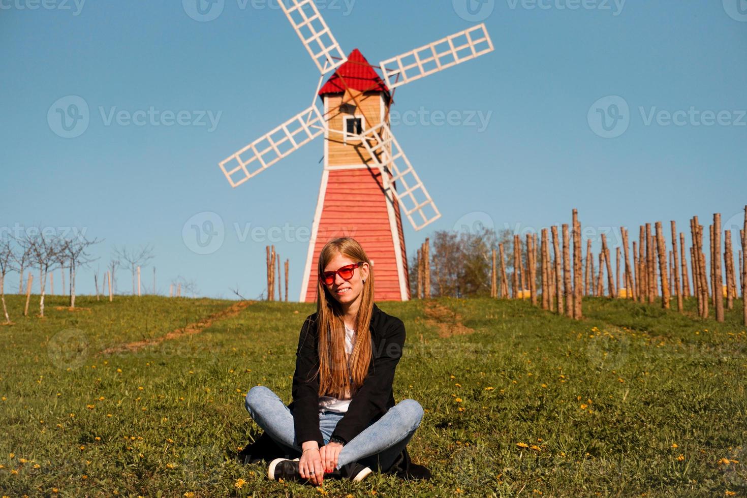 schöne junge frau sitzt auf dem gras gegen die mühle foto