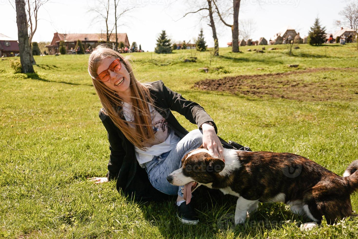 junge Frau mit roter Sonnenbrille spielt mit ihrem Corgi foto