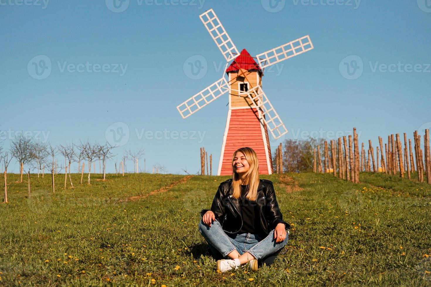 schöne junge frau sitzt auf dem gras gegen die mühle foto