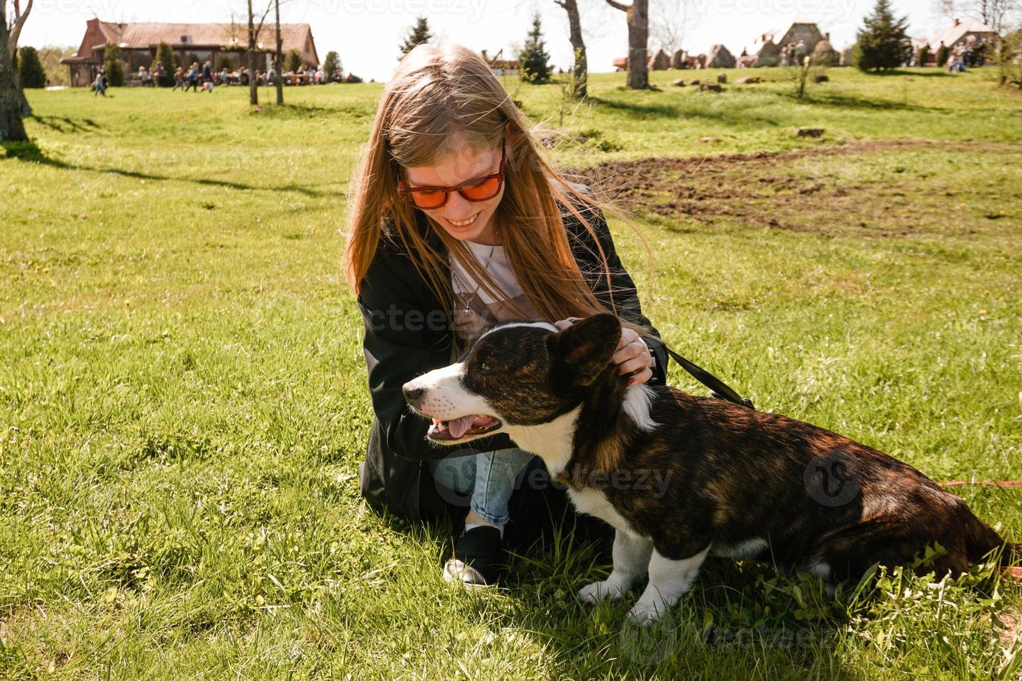 junge Frau mit roter Sonnenbrille spielt mit ihrem Corgi foto