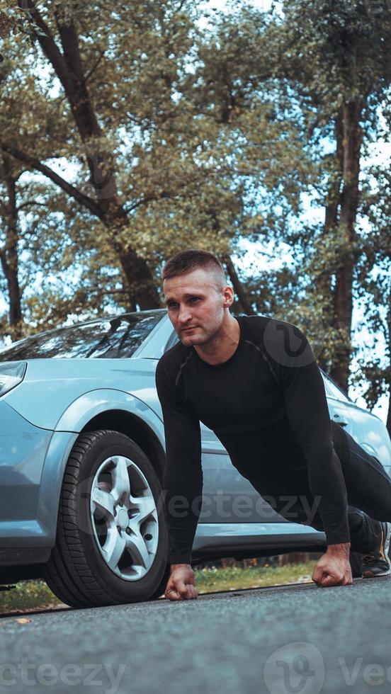 gut aussehender Mann in der Nähe des Autos. der Athlet neben der Maschine ausgewrungen foto