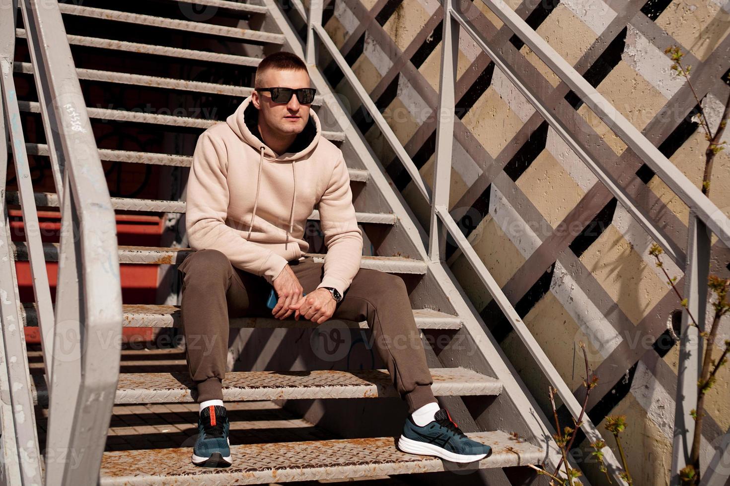 ein junger mann sitzt auf den treppen in der stadt. urbaner Stil foto