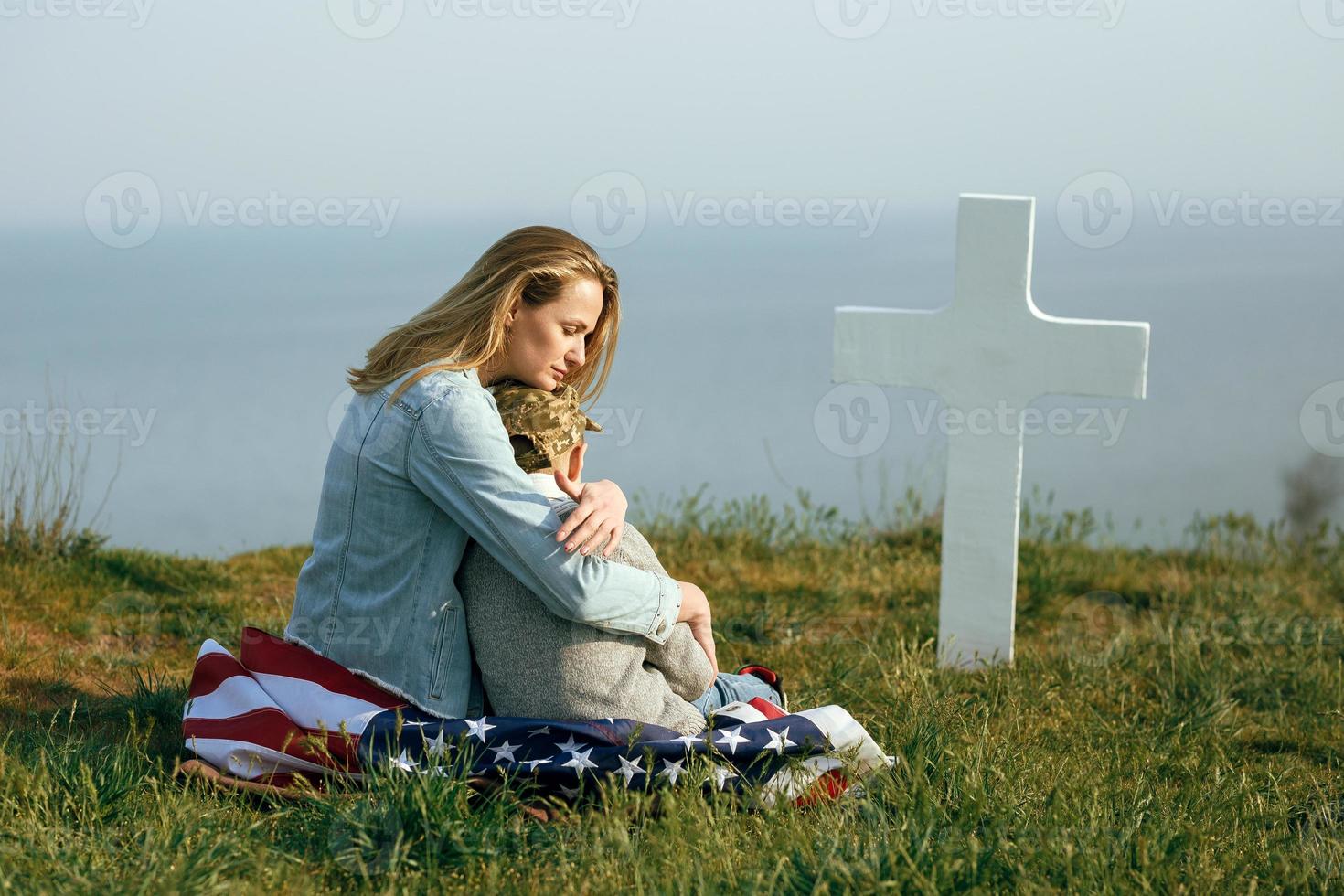 Mama und Sohn sitzen auf dem Grab eines Soldaten foto