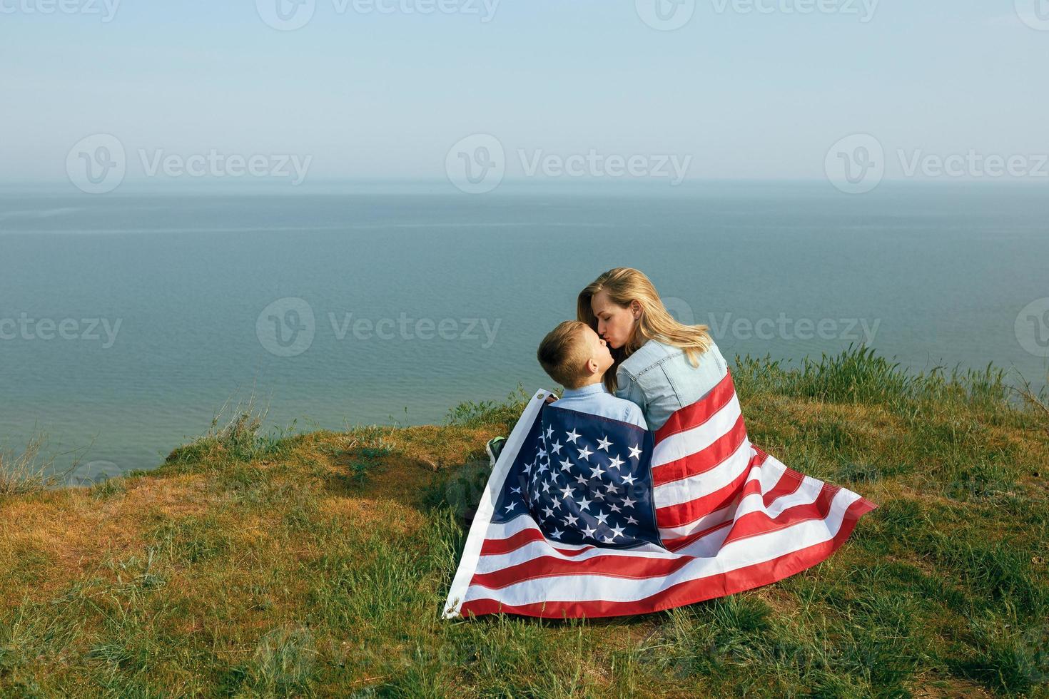 Frau und ihr Kind gehen mit der USA-Flagge an der Ozeanküste foto