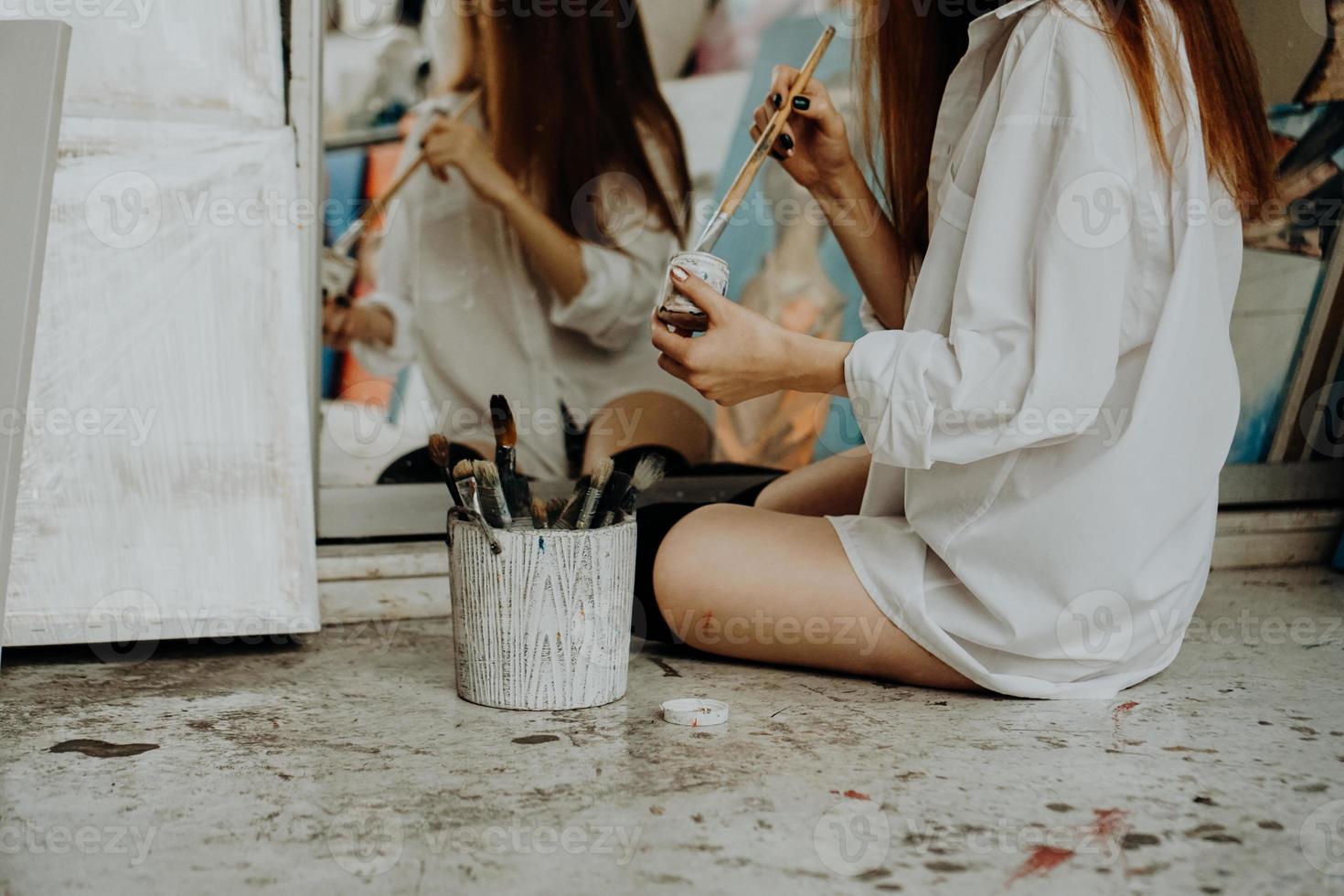 Malerin sitzt auf dem Boden vor dem Spiegel. Kunstatelier foto