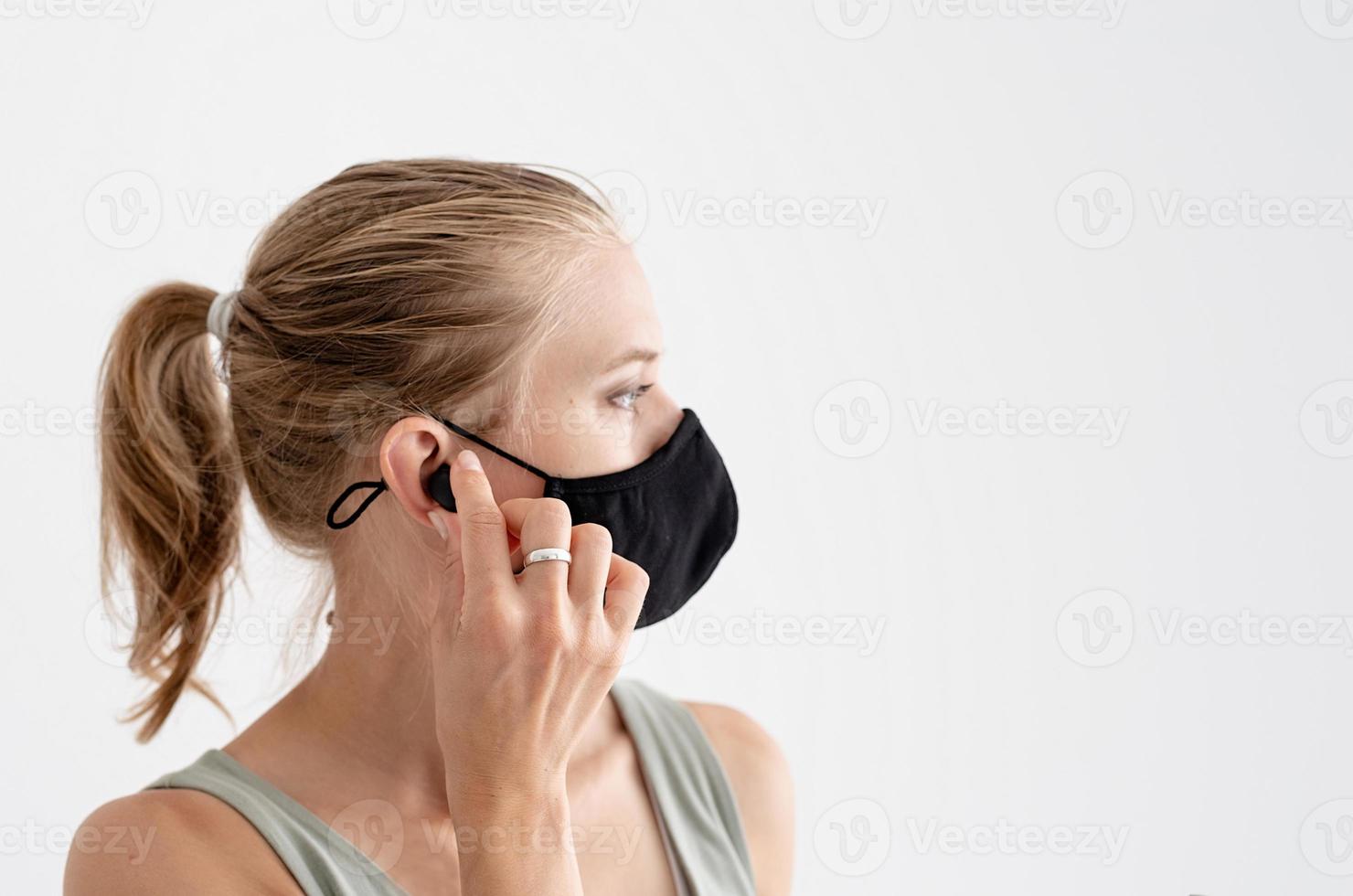 junge Frau in einer Schutzmaske mit drahtlosen Ohrhörern foto