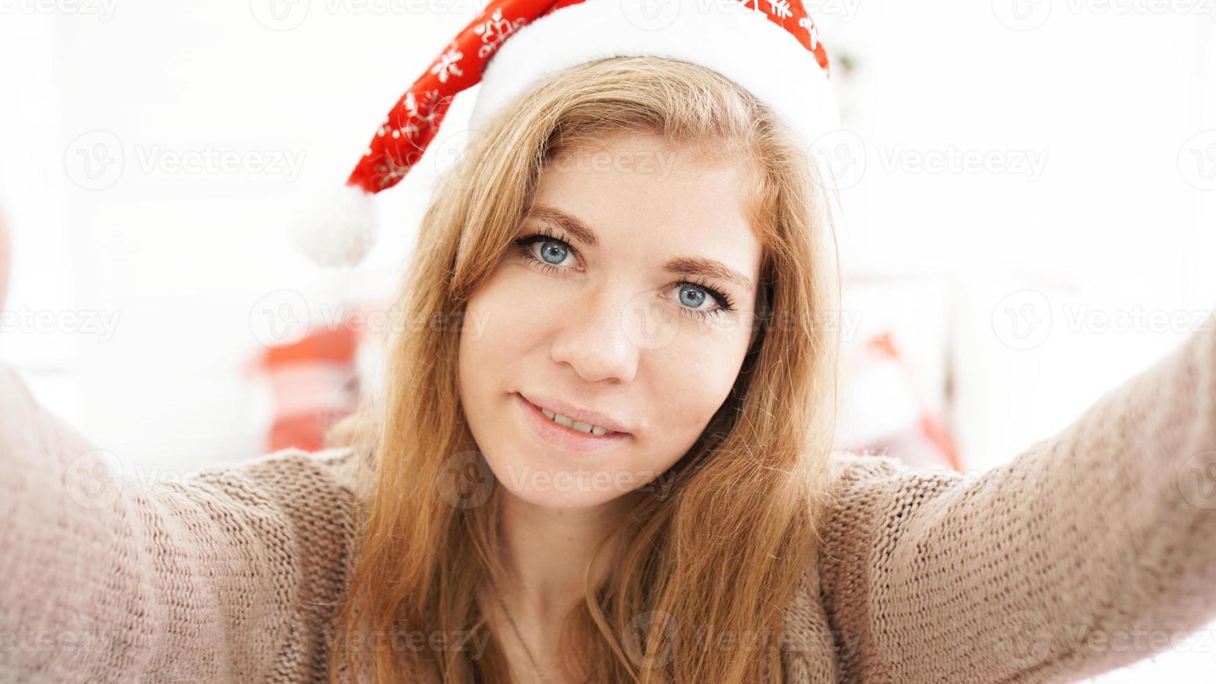 Weihnachtsporträt des schönen Mädchens. Teenager mit Weihnachtsmann-Hut foto