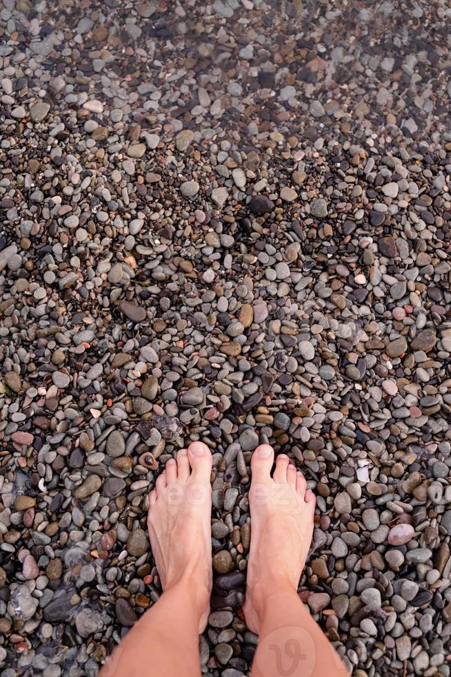 nackte weibliche Füße am Kieselsteinstrand, Ansicht von oben foto