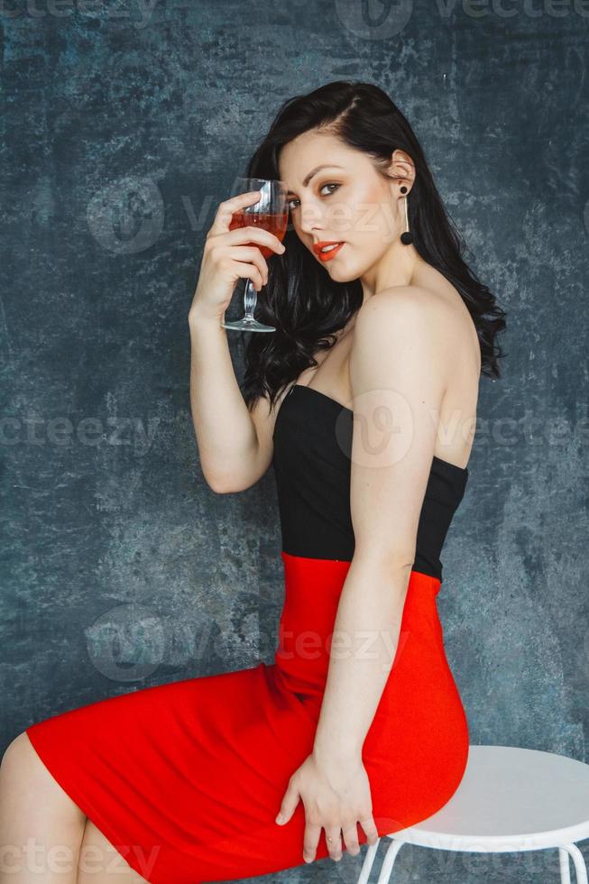 schöne Frau mit Glas Wein auf grauem Hintergrund foto