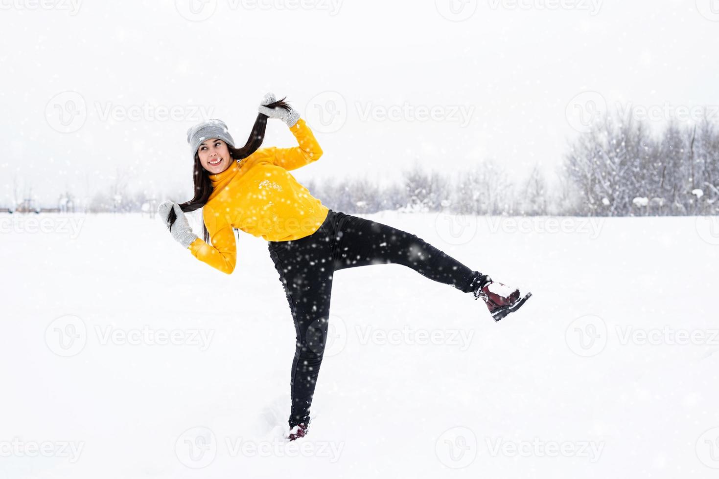 junge brünette Frau, die mit Schnee im Park spielt foto