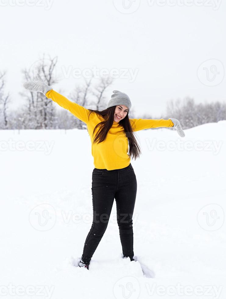 junge brünette Frau, die mit Schnee im Park spielt foto