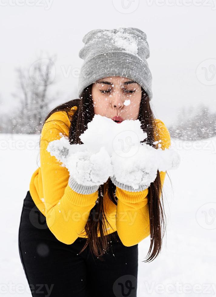 junge brünette Frau, die mit Schnee im Park spielt foto