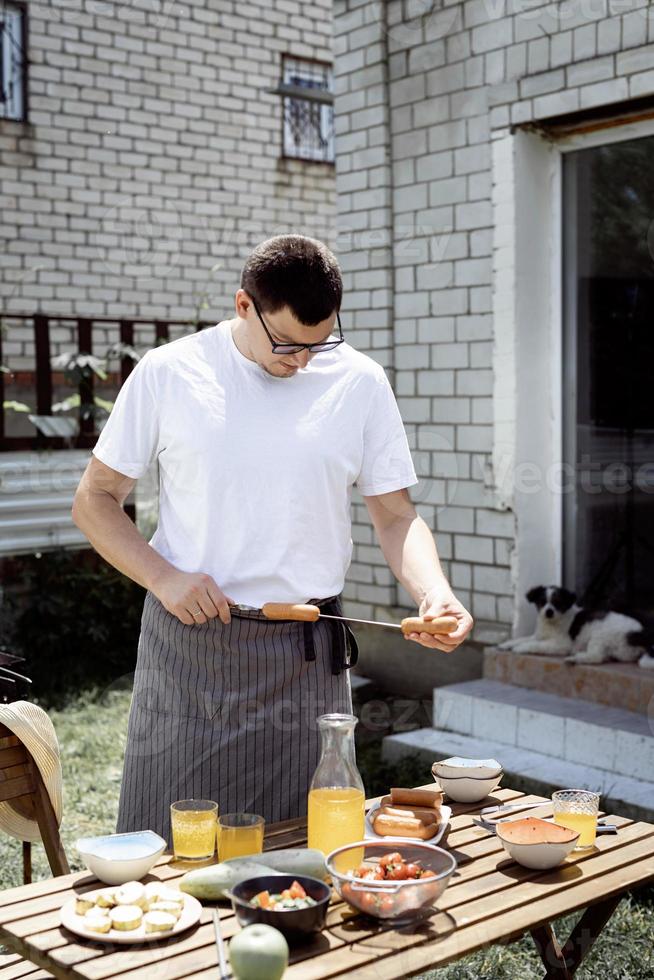 junger Mann grillt Kebabs am Spieß, Mann grillt Fleisch im Freien foto