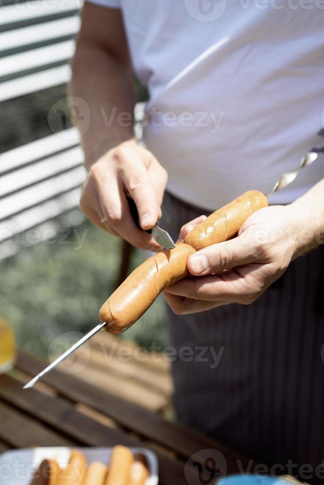 junger Mann grillt Kebabs am Spieß, Mann grillt Fleisch im Freien foto