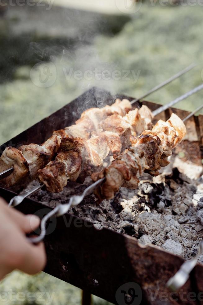 Nahaufnahme von Kebabs am Spieß, Mann Grillen von Fleisch im Freien foto