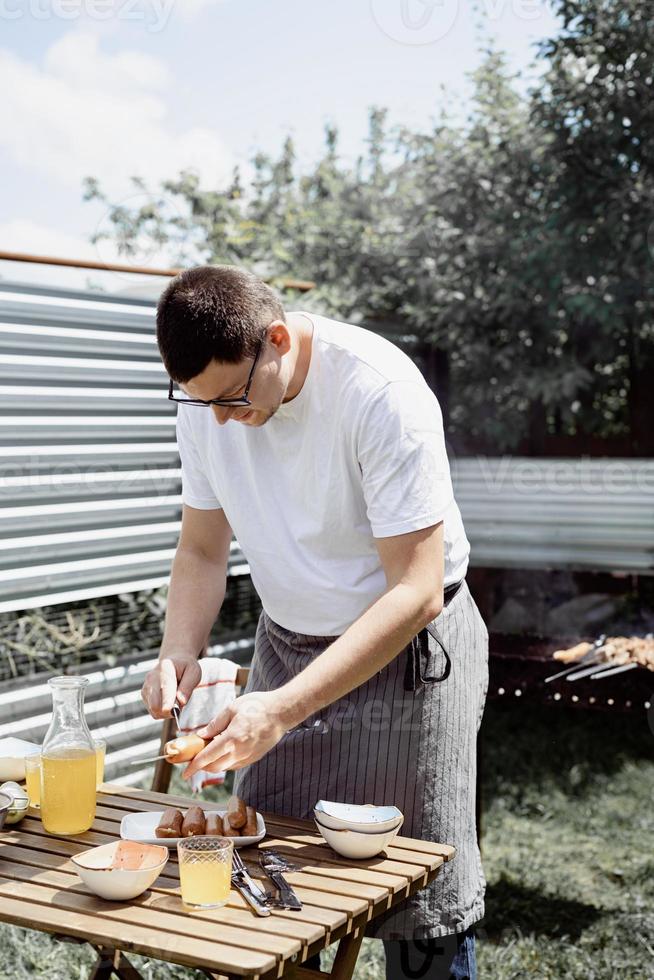 junger Mann grillt Kebabs am Spieß, Mann grillt Fleisch im Freien foto