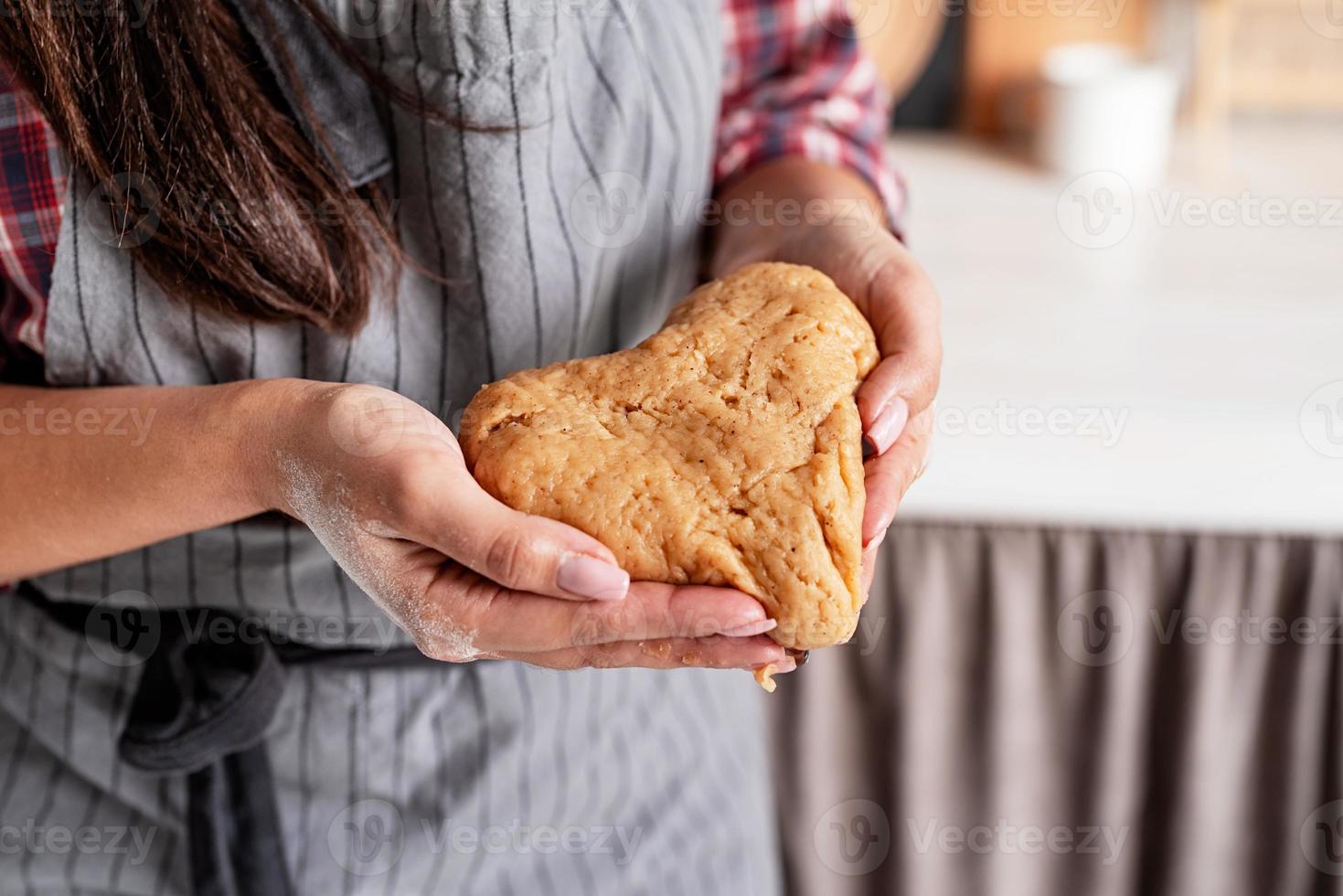 Frauenhände halten herzförmigen Teig foto