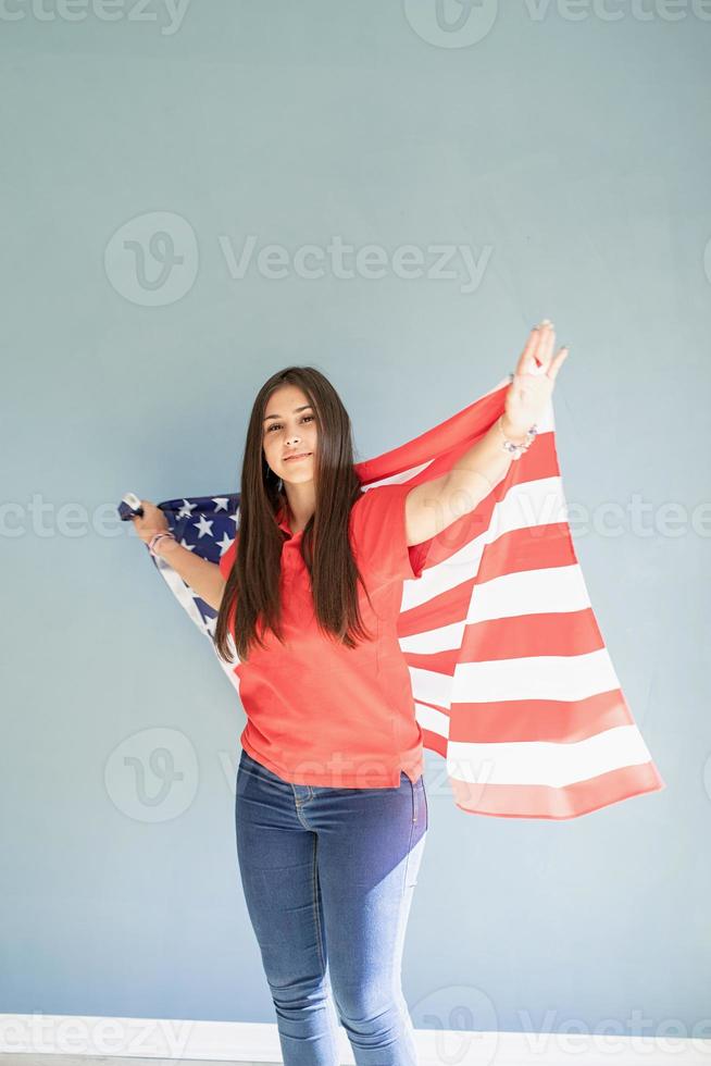 glückliche junge Frau mit amerikanischer Flagge auf blauem Hintergrund foto