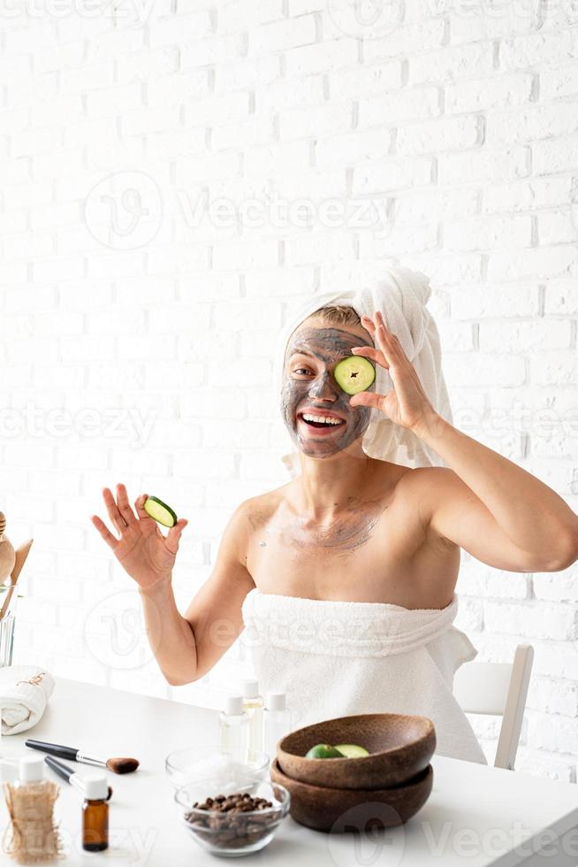 junge Frau, die mit einer Kosmetikbürste eine Spa-Gesichtsmaske auf ihr Gesicht aufträgt foto