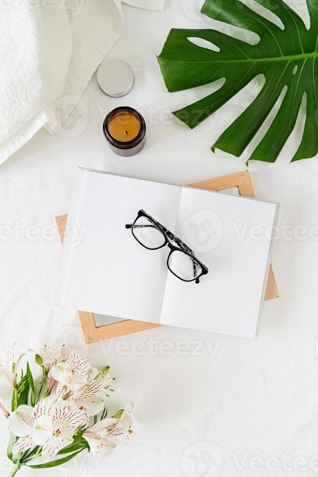 aufgeschlagenes Buch, Gläser, Kerze und Blumen Draufsicht foto