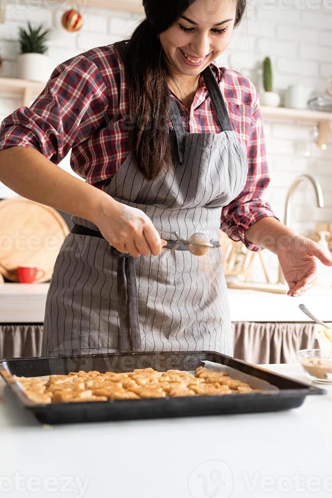 Frau backt Kekse in der Küche und gießt Kakaopulver ein foto