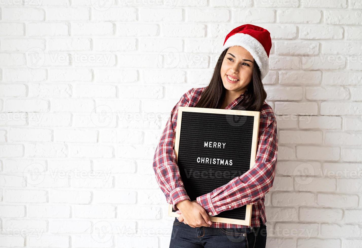 Frau in Weihnachtsmütze mit schwarzer Buchstabentafel foto