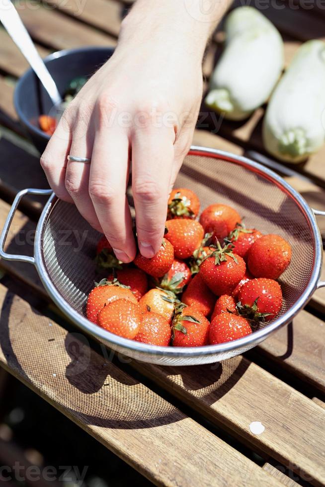 Mannhand hält einen Eimer mit Erdbeeren foto