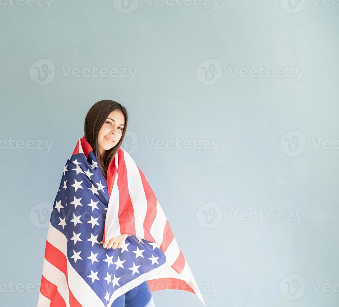 schöne junge Frau mit amerikanischer Flagge auf blauem Hintergrund foto