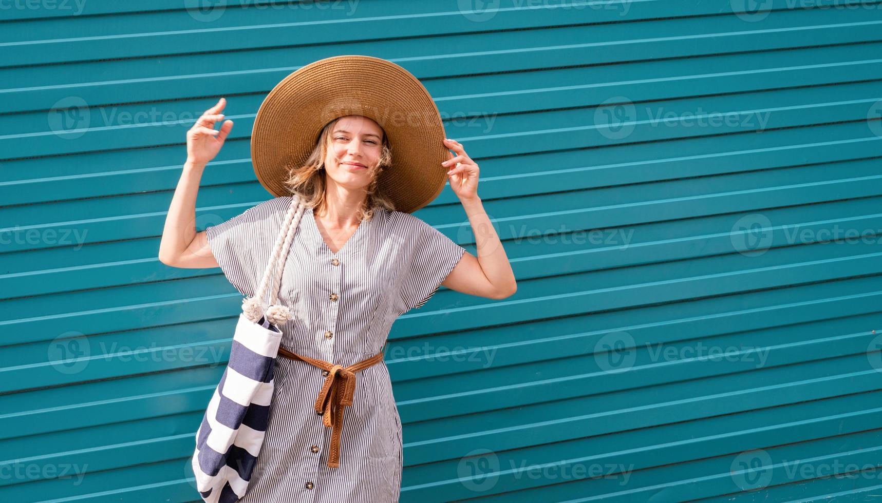 Frau steht an einem windigen Tag auf der Straße neben der blauen Wand foto