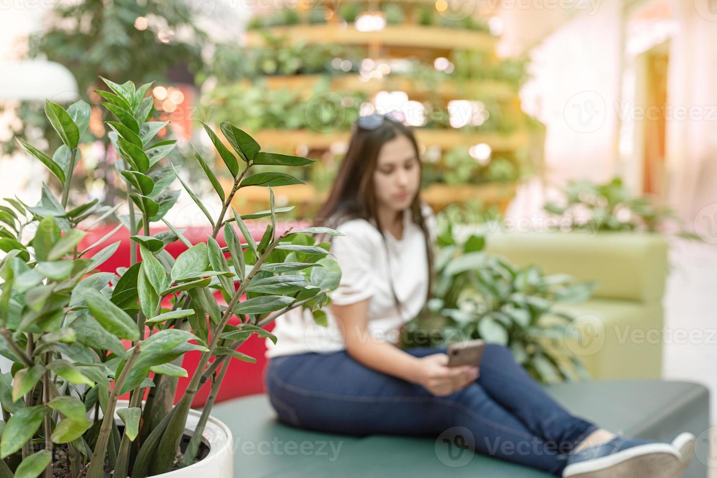 Frau auf der Couch im Einkaufszentrum und schaut auf das Telefon foto