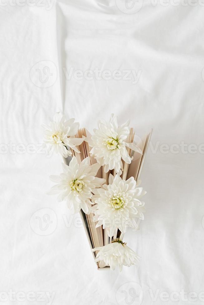 Buch mit weißen Chrysanthemenblüten auf weißem Hintergrund foto