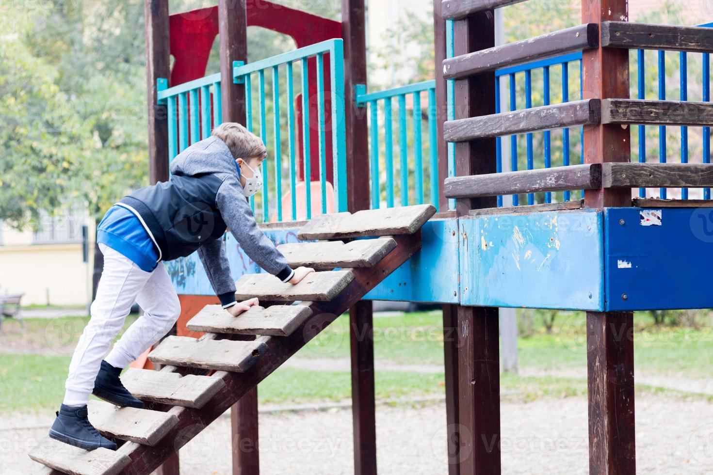 kleiner Junge, der aufgrund einer Coronavirus-Pandemie allein auf dem Spielplatz spielt. foto