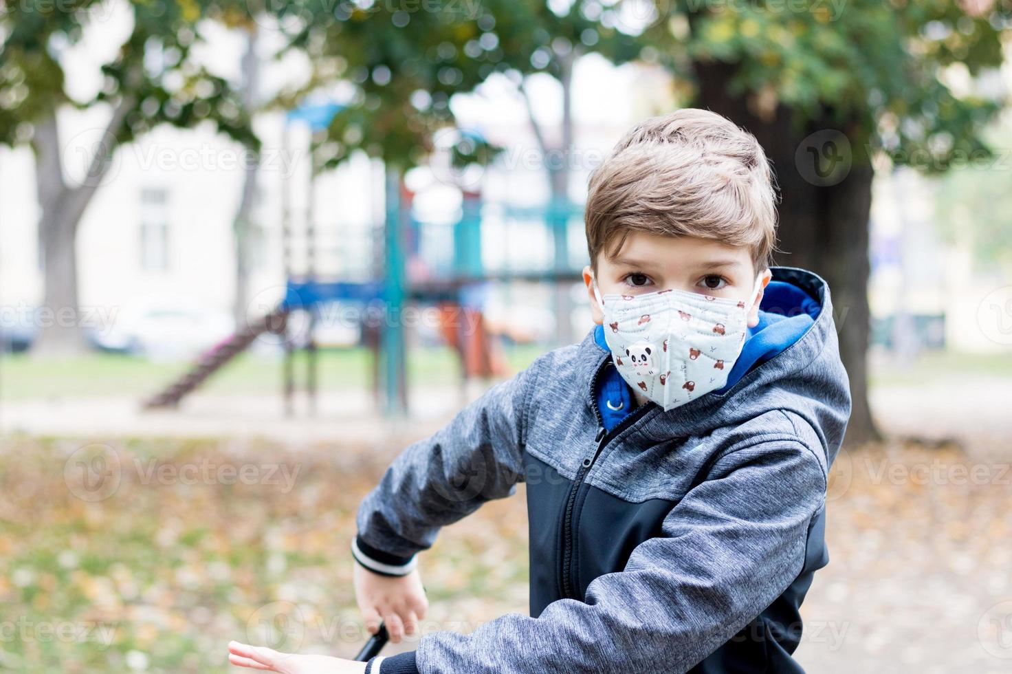 kleiner Junge mit Gesichtsschutzmaske im Park. foto