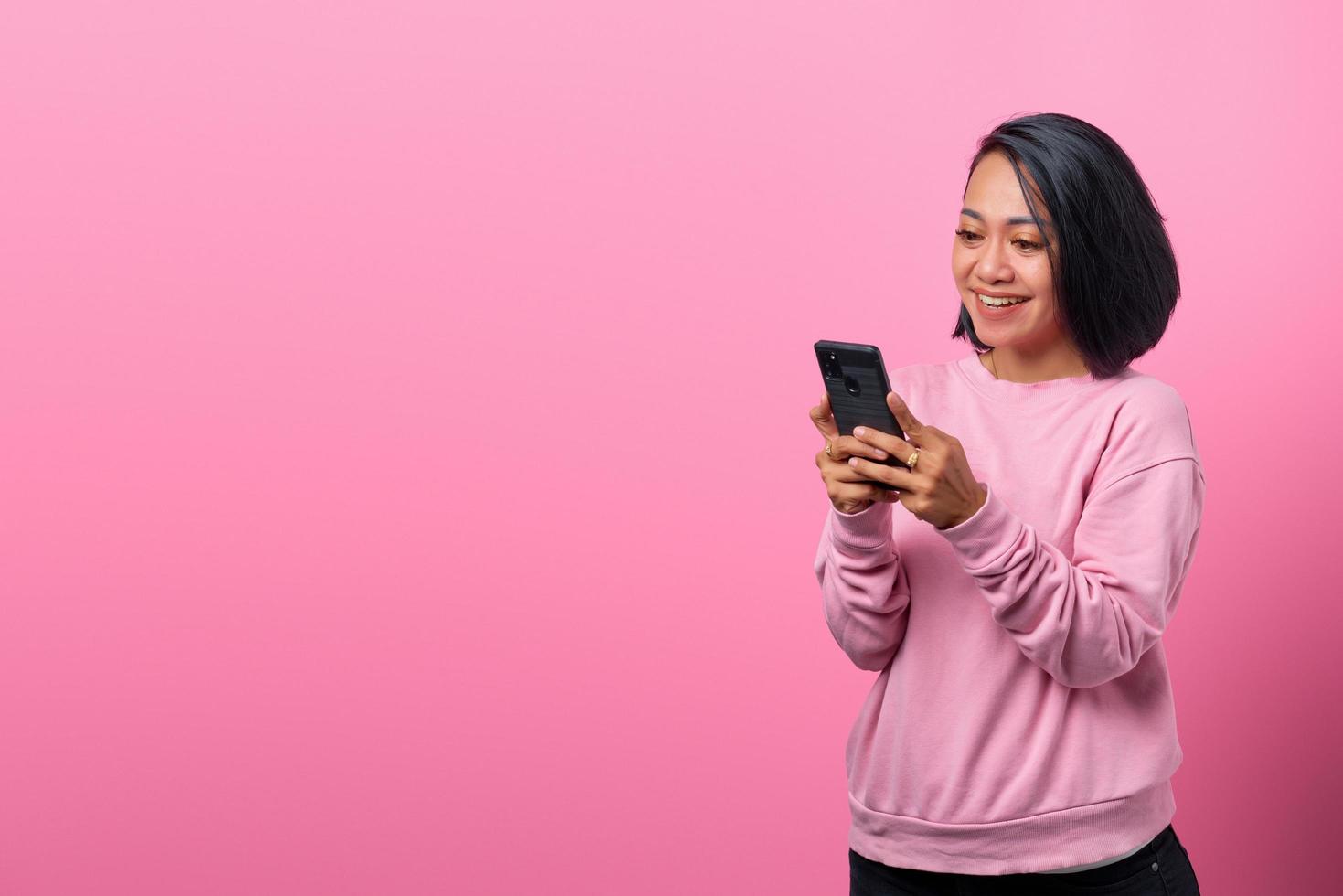 fröhliche junge Asiatin mit Smartphone mit lächelndem Gesicht foto