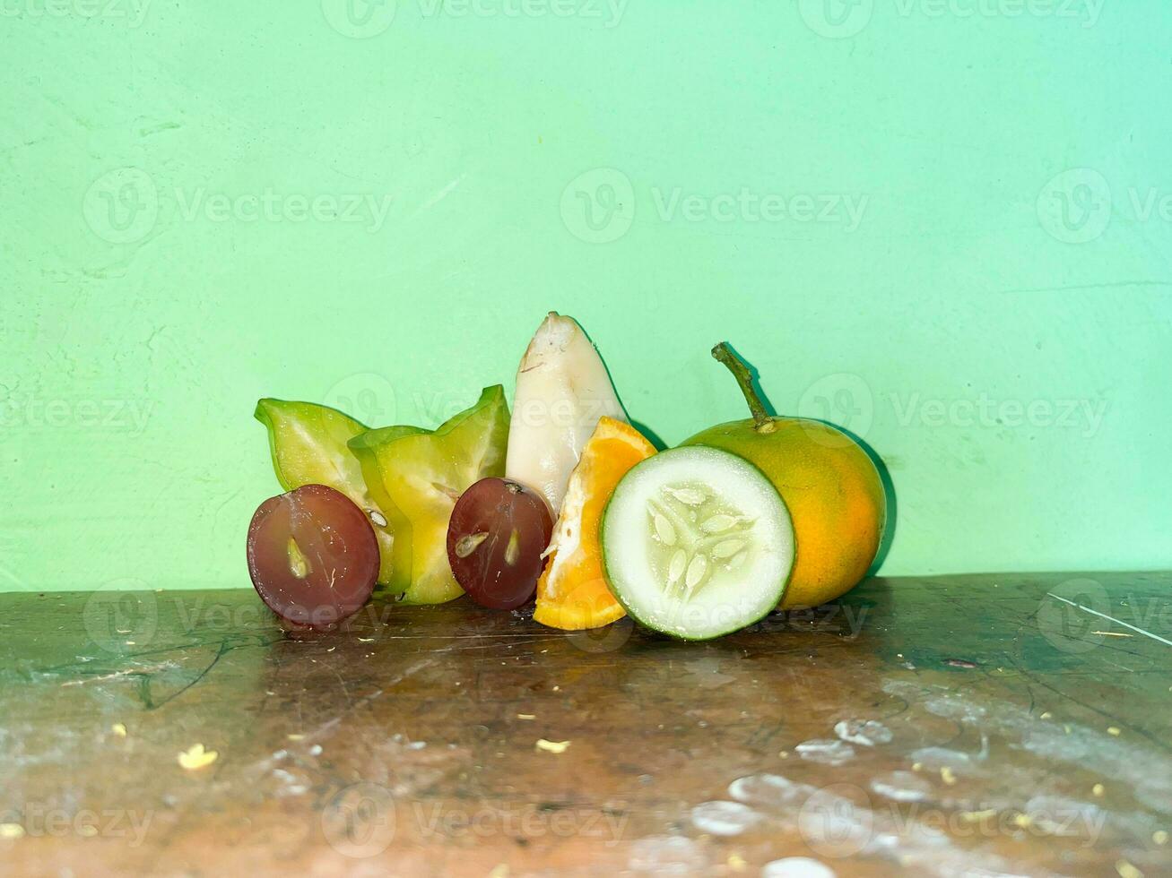 Stücke von Frucht. verschiedene Stücke von Star Frucht, Trauben, Orangen, Gurken, salak Obst auf Tabelle foto