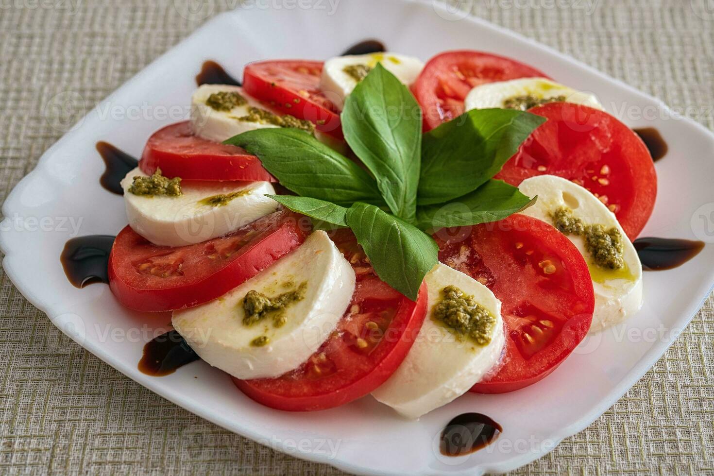 Teller von gesund klassisch köstlich Caprese Salat mit Tomaten und Mozzarella Käse mit frisch Basilikum Blätter auf Licht Leinen- Tischdecke. Italienisch Küche Konzept foto