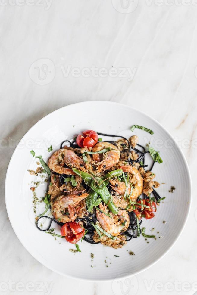 Gourmet-Essen gegrillte Garnelen und Gemüse auf schwarzem Tintenfisch-Tinten-Nudeln foto