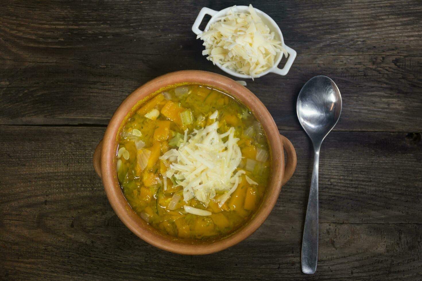 Kasserolle mit heiß Gemüse Suppe und gerieben Käse auf rustikal Holz foto