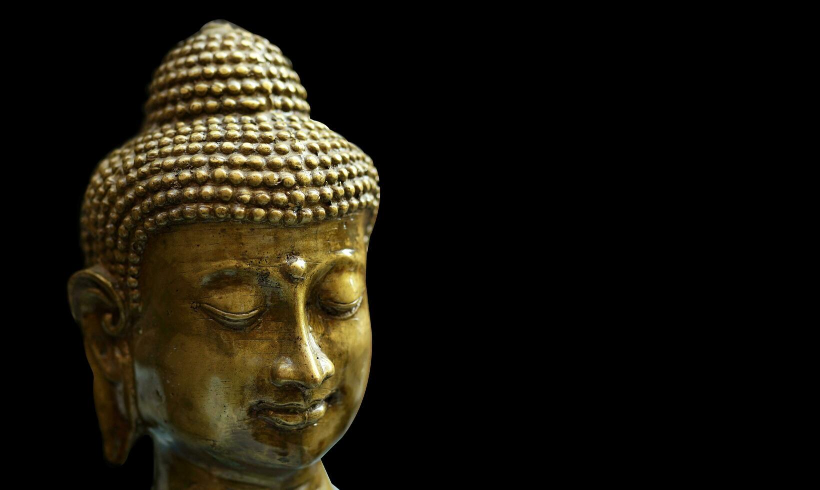 golden Statue von ein lächelnd Buddha Kopf auf ein schwarz Hintergrund foto