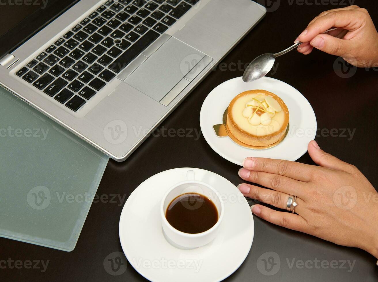 Nahansicht. Overhead Aussicht von ein weiblich Hand halten ein Tee Löffel Über ein Französisch Dessert mit Zitrone Pudding foto