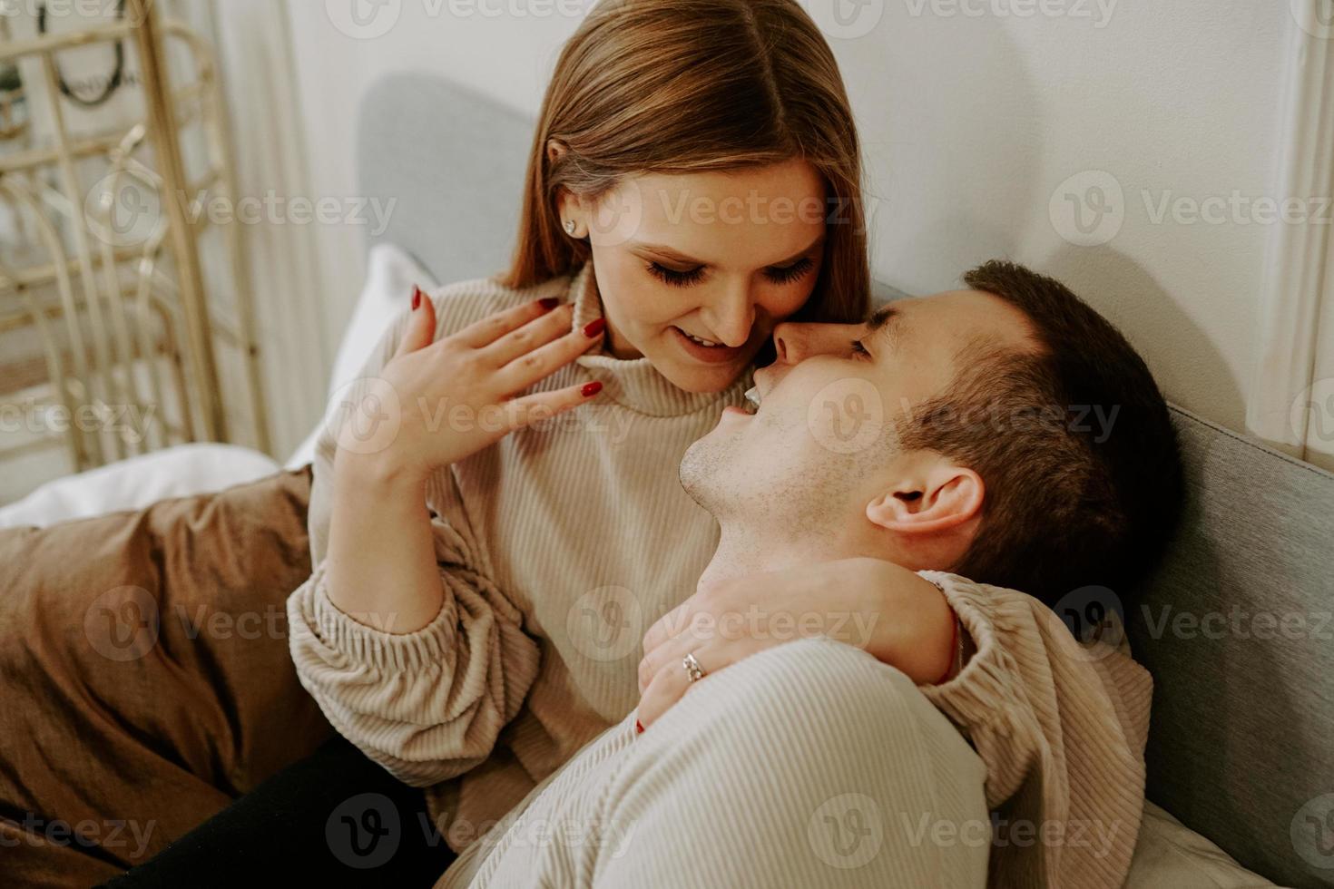 Nahaufnahmeporträt eines schönen jungen küssenden Paares im Bett zu Hause foto