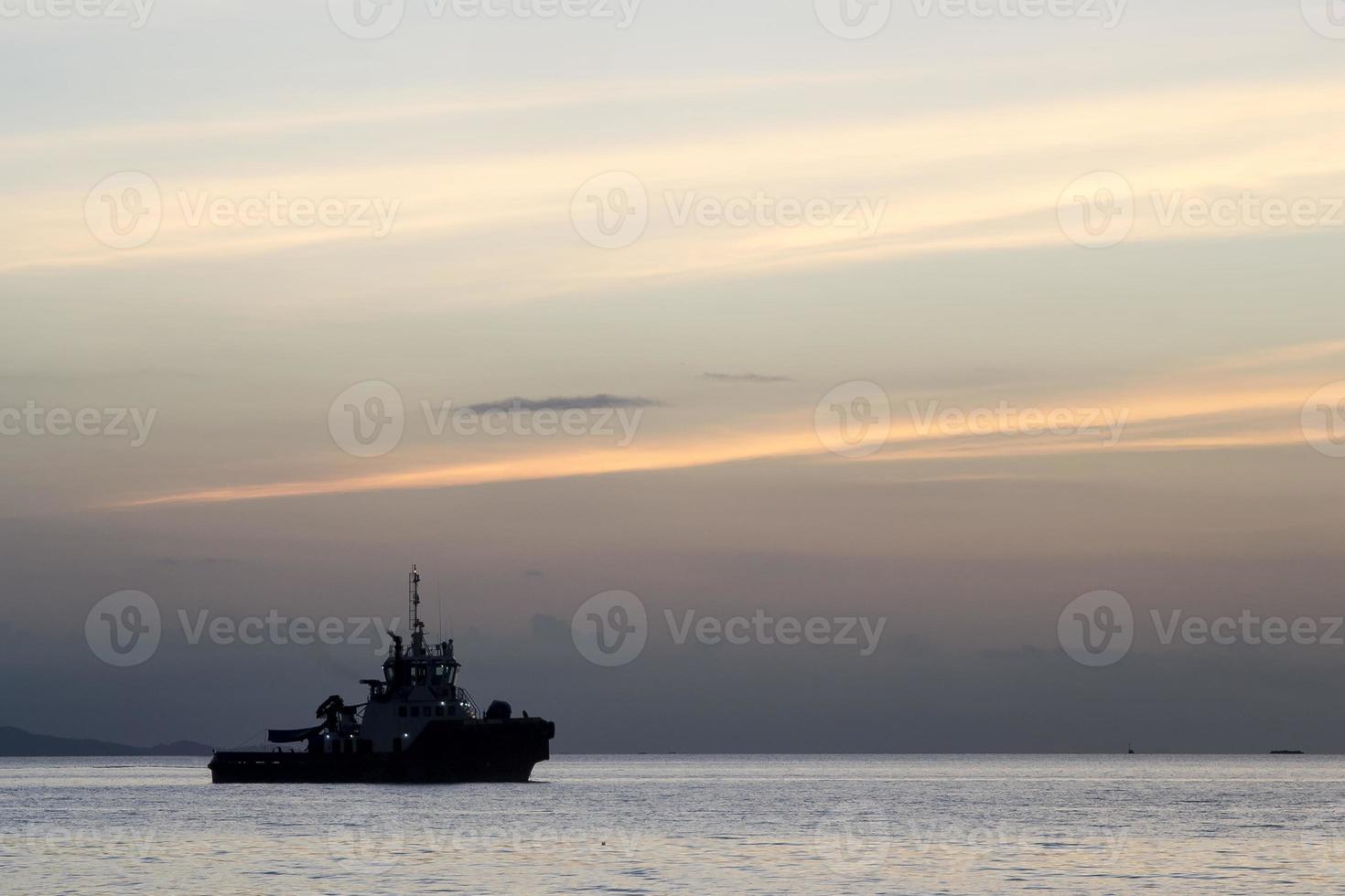 der Sonnenunterganghimmelhintergrund mit Schiffssilhouette, die am Meer festmacht foto