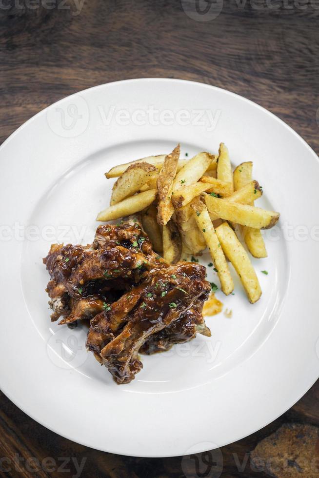 würzige BBQ-Barbecue-Schweinerippchen mit Wedges Pommes frites foto