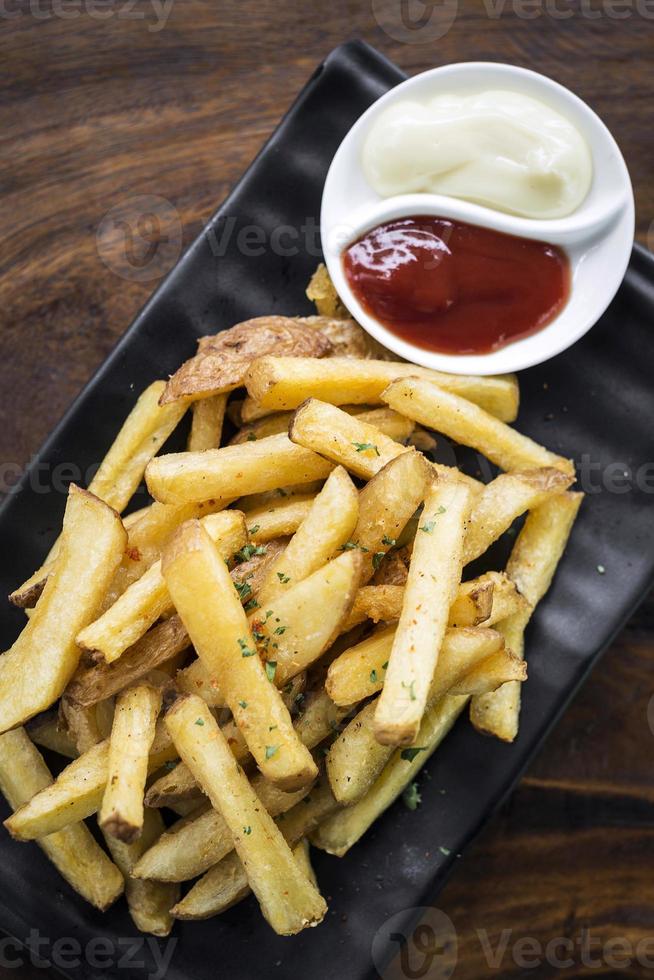 Pommes Frites Beilage Snack mit Dip Saucen auf Holztisch foto