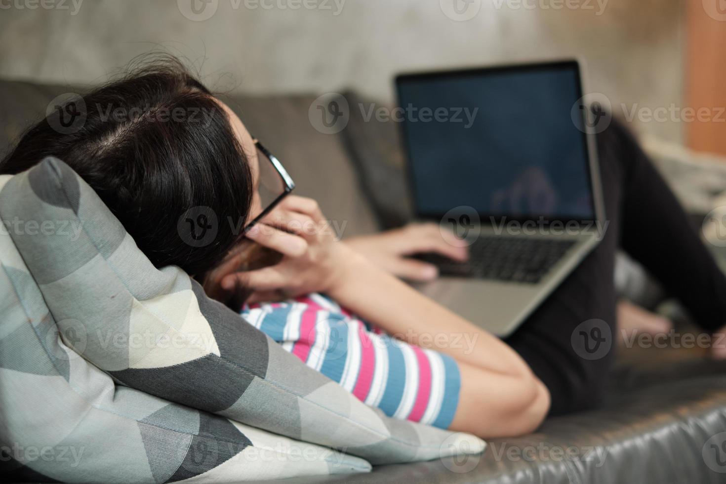 asiatische Frau, die zu Hause arbeitet, sich hinlegt und ein Mobiltelefon benutzt. foto