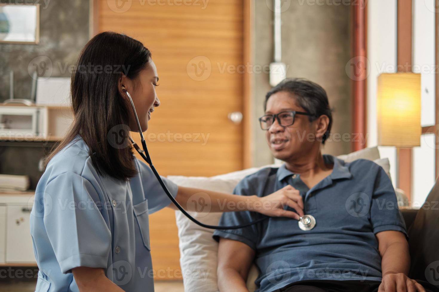 Ärztin, die die Gesundheit des asiatischen älteren männlichen Patienten zu Hause überprüft. foto